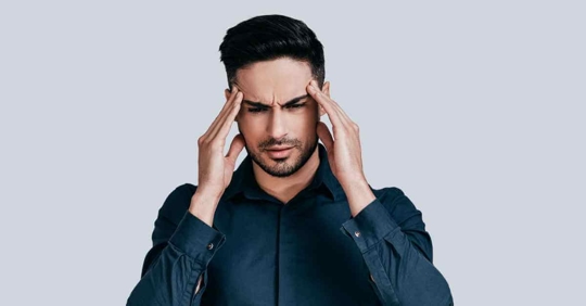 A man standing with his hands to his head. He appears frustrated or upset